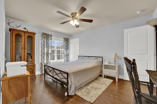 bedroom featuring dark wood finished floors, a textured ceiling, and baseboards