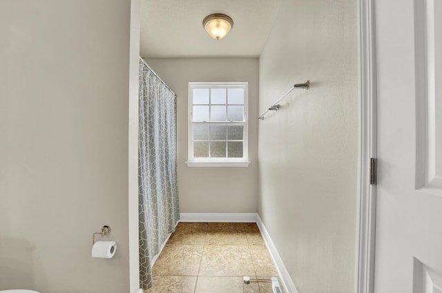 full bathroom featuring tile patterned flooring, a shower with shower curtain, and baseboards