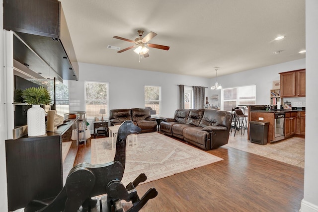 living room featuring light wood finished floors, recessed lighting, visible vents, and ceiling fan with notable chandelier