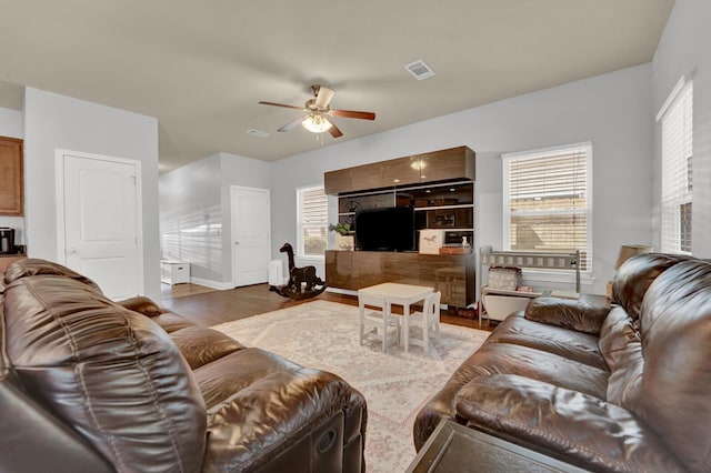 living room featuring a ceiling fan, visible vents, and wood finished floors