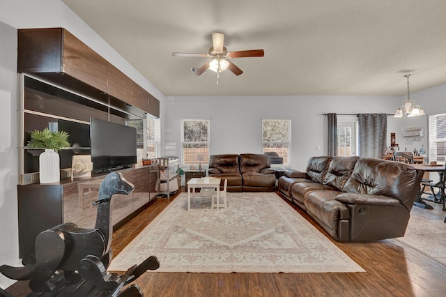 living room featuring ceiling fan with notable chandelier, wood finished floors, and visible vents