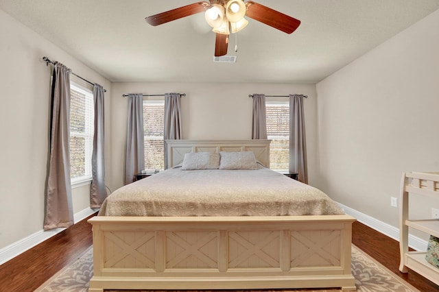 bedroom featuring ceiling fan, baseboards, visible vents, and dark wood finished floors