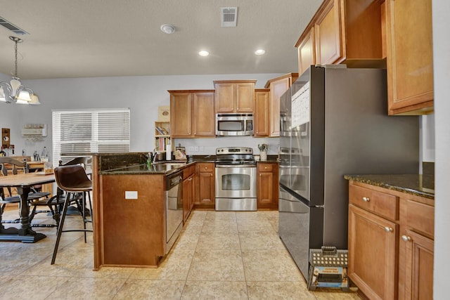 kitchen with a peninsula, appliances with stainless steel finishes, visible vents, and brown cabinets