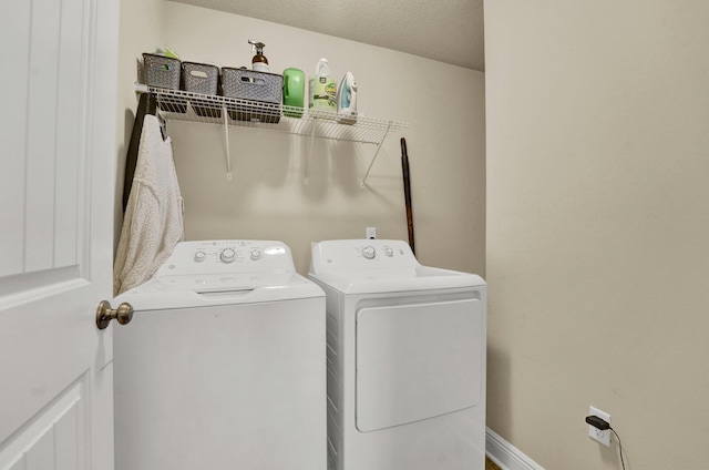 laundry area with baseboards, laundry area, a textured ceiling, and washer and dryer