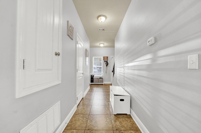 hallway featuring visible vents, baseboards, and tile patterned floors