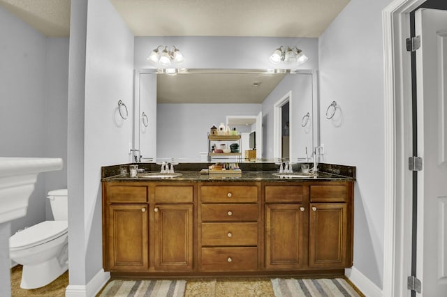 full bath with double vanity, a sink, toilet, and baseboards