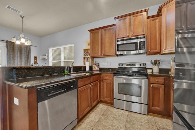 kitchen featuring a peninsula, a sink, visible vents, appliances with stainless steel finishes, and brown cabinetry