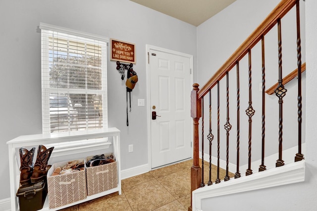 foyer featuring tile patterned flooring, stairs, and baseboards