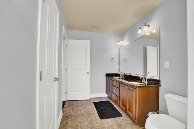 bathroom with toilet, double vanity, a sink, and visible vents