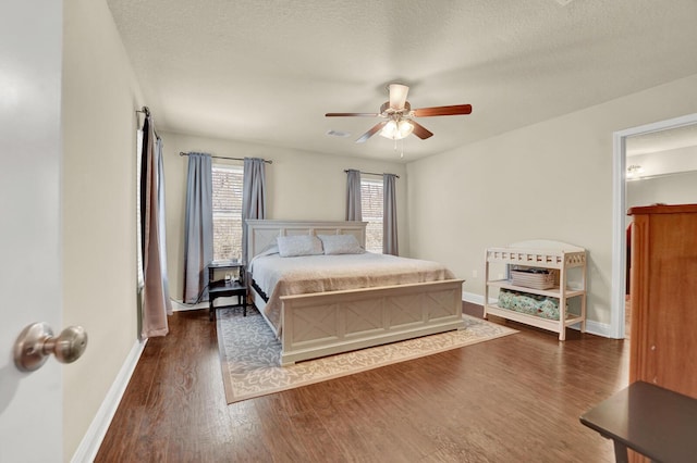 bedroom featuring a textured ceiling, dark wood-style flooring, and baseboards