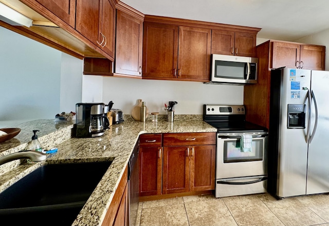 kitchen with a sink, light stone countertops, and appliances with stainless steel finishes