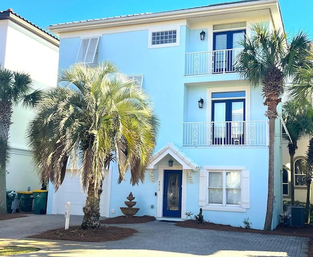 view of front of property featuring a garage, decorative driveway, a balcony, and stucco siding