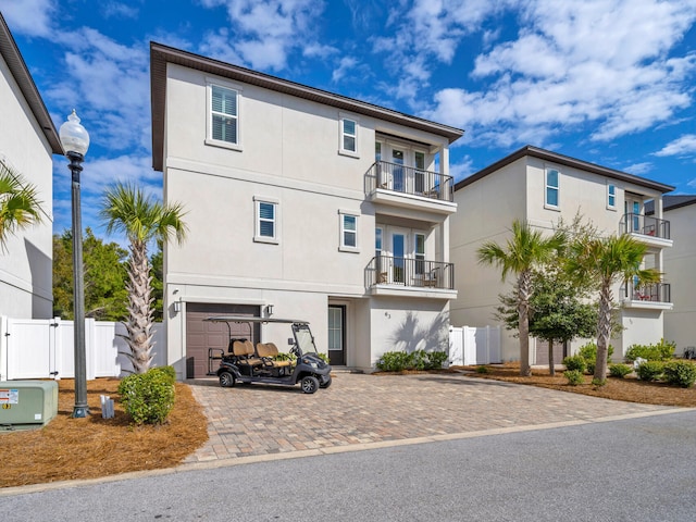 exterior space with decorative driveway, fence, an attached garage, and stucco siding