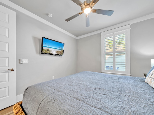 bedroom featuring ceiling fan, crown molding, and wood finished floors