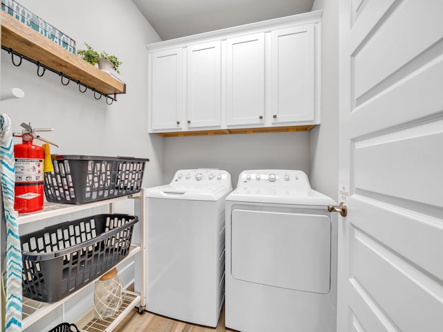 laundry room featuring cabinet space, light wood-style flooring, and washer and dryer