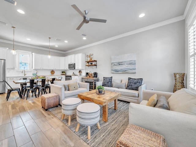 living area featuring ornamental molding, recessed lighting, light wood-style floors, and a ceiling fan