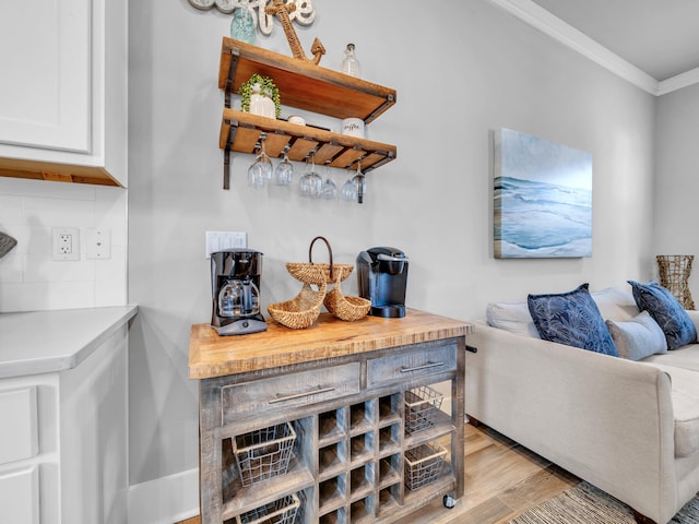 bar with tasteful backsplash, light wood-style floors, and crown molding