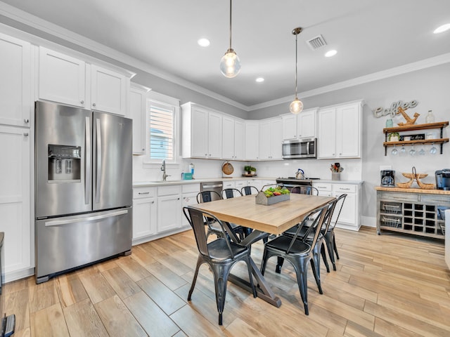 kitchen featuring stainless steel appliances, a sink, visible vents, light countertops, and ornamental molding