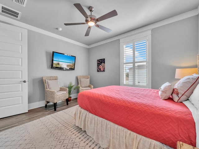 bedroom featuring baseboards, visible vents, ceiling fan, wood finished floors, and crown molding