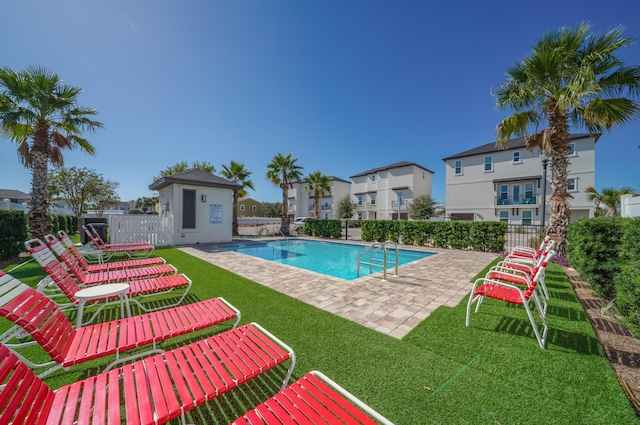 pool with a patio area, fence, an outbuilding, and a yard