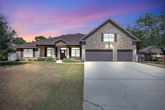 view of front facade with a shingled roof, concrete driveway, fence, a yard, and brick siding