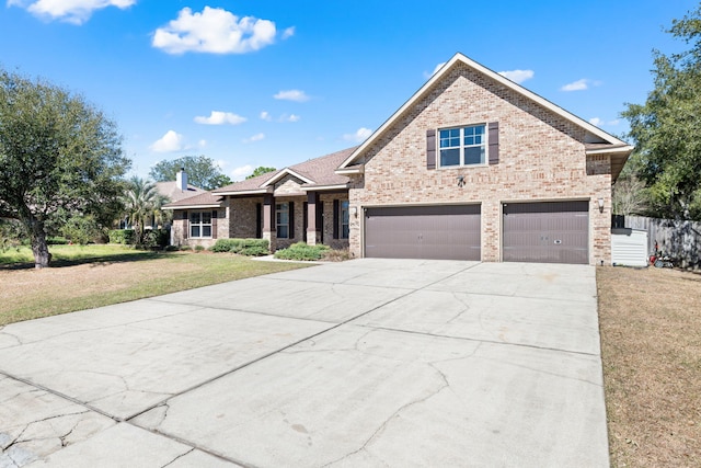 view of front facade featuring brick siding, a chimney, concrete driveway, an attached garage, and a front yard