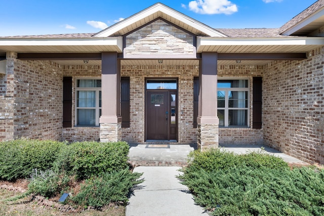 doorway to property with stone siding, covered porch, and brick siding