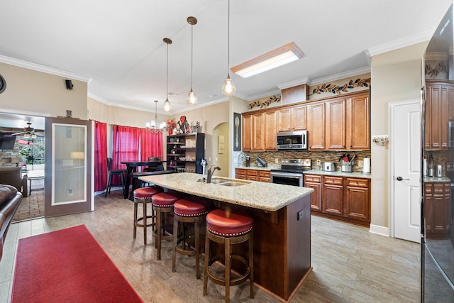 kitchen featuring stainless steel appliances, a sink, a kitchen breakfast bar, backsplash, and light wood finished floors