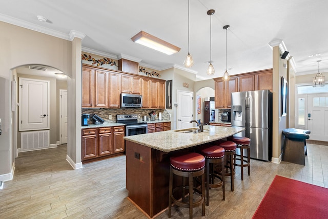 kitchen with arched walkways, stainless steel appliances, backsplash, a sink, and a kitchen bar