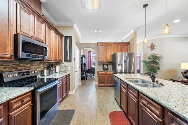 kitchen featuring arched walkways, hanging light fixtures, stainless steel appliances, crown molding, and a sink