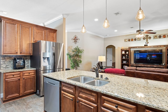 kitchen with arched walkways, stainless steel appliances, visible vents, ornamental molding, and a sink