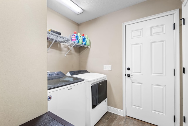 laundry room featuring laundry area, baseboards, dark wood-type flooring, a textured ceiling, and washer and dryer