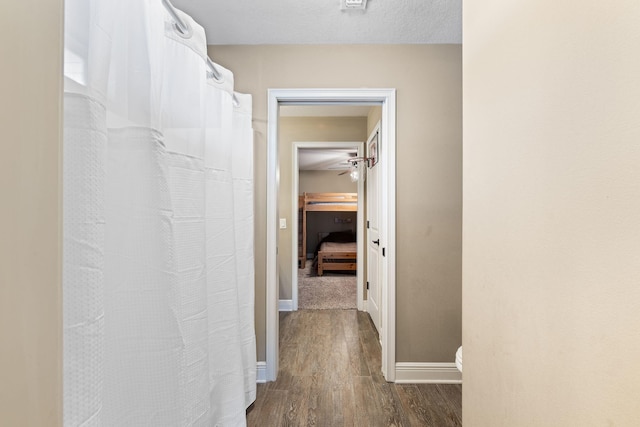 corridor with dark wood-style flooring and baseboards