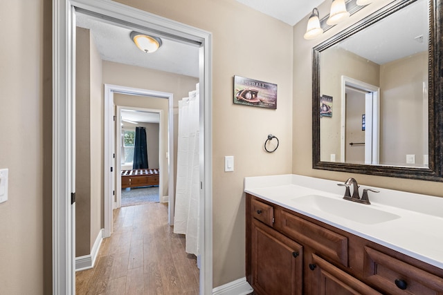 bathroom featuring baseboards, wood finished floors, and vanity