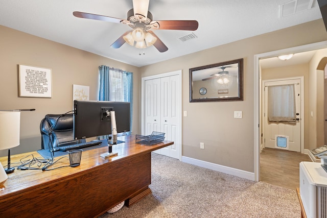 carpeted home office with arched walkways, visible vents, ceiling fan, and baseboards