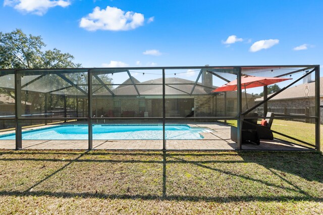 outdoor pool with a yard, a patio, and glass enclosure