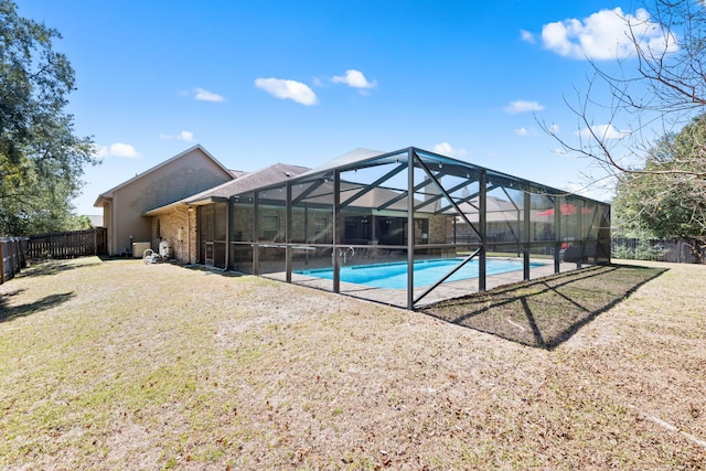 view of pool featuring a yard, glass enclosure, a fenced backyard, and a fenced in pool