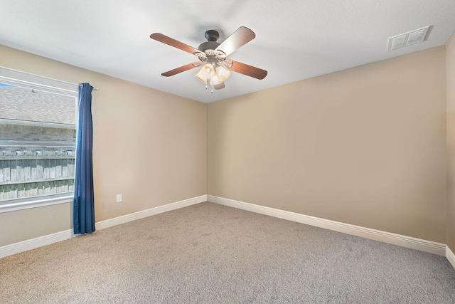 carpeted empty room with ceiling fan, visible vents, and baseboards