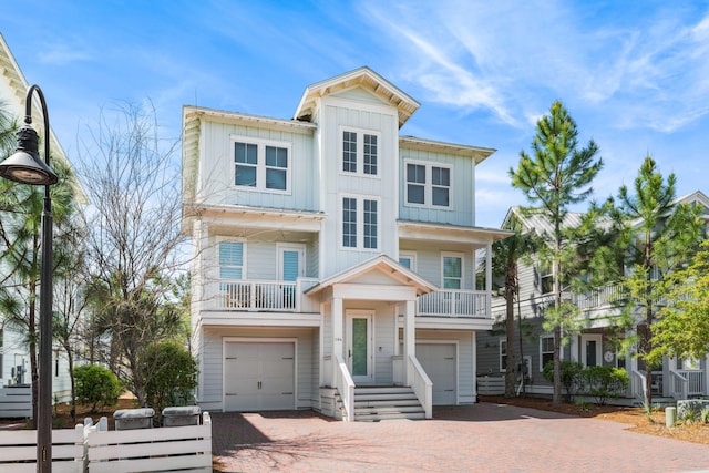 raised beach house featuring board and batten siding, decorative driveway, and a garage