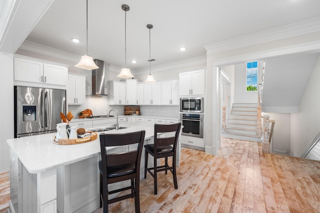 kitchen featuring stainless steel appliances, tasteful backsplash, wall chimney exhaust hood, and a sink