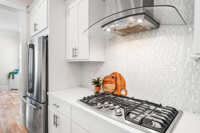 kitchen with appliances with stainless steel finishes, light countertops, wall chimney exhaust hood, and tasteful backsplash