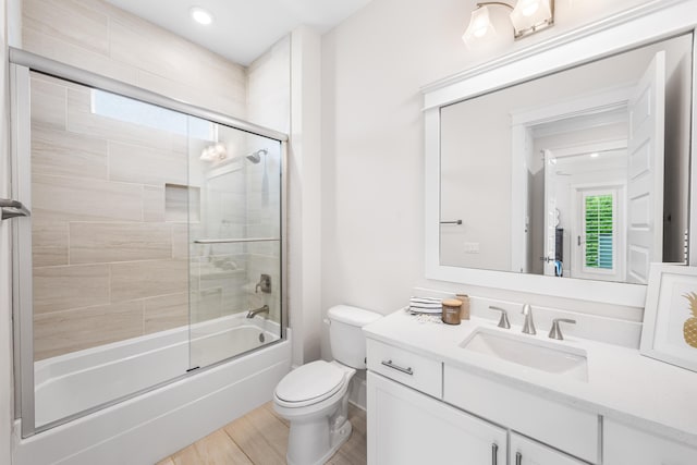 full bathroom with wood finished floors, vanity, toilet, and bath / shower combo with glass door