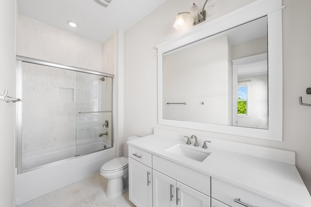 full bathroom featuring toilet, bath / shower combo with glass door, and vanity