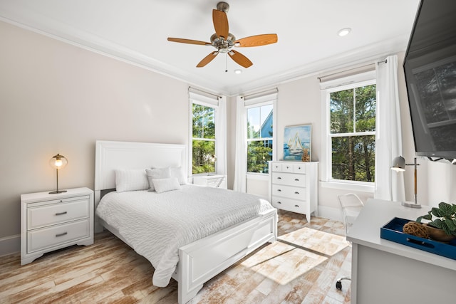 bedroom featuring light wood-type flooring, multiple windows, crown molding, and baseboards