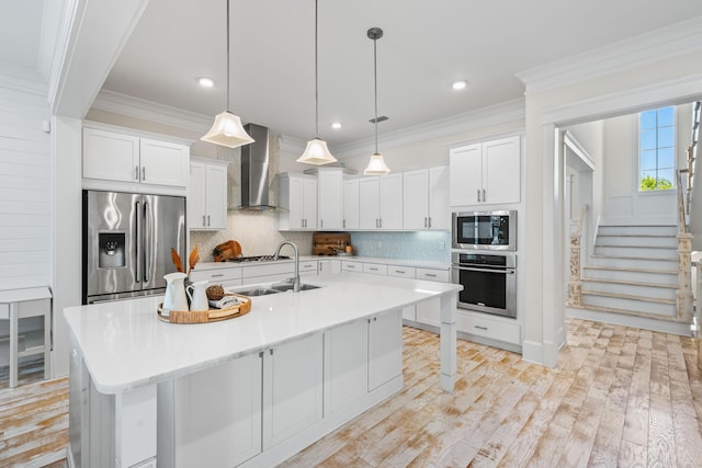 kitchen with stainless steel appliances, tasteful backsplash, wall chimney exhaust hood, and white cabinets