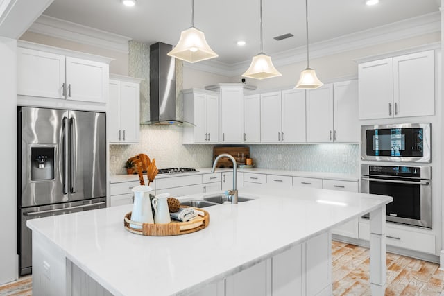 kitchen with stainless steel appliances, crown molding, a sink, and wall chimney range hood