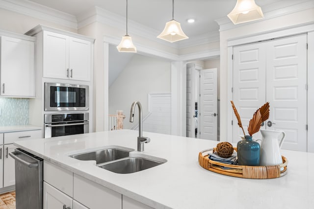 kitchen with a sink, white cabinets, appliances with stainless steel finishes, decorative backsplash, and crown molding