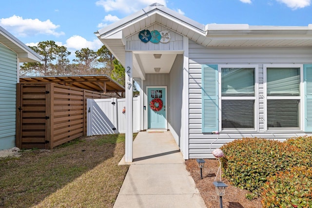 view of exterior entry featuring a gate, fence, and a yard