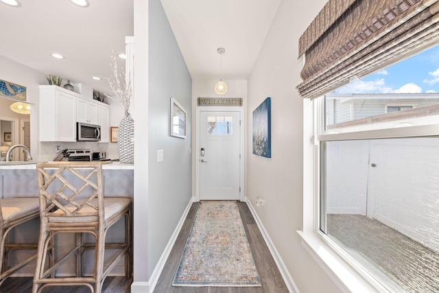 doorway to outside with a sink, baseboards, wood finished floors, and recessed lighting