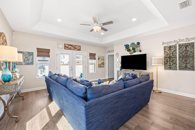 living area featuring wood finished floors, visible vents, baseboards, french doors, and a raised ceiling